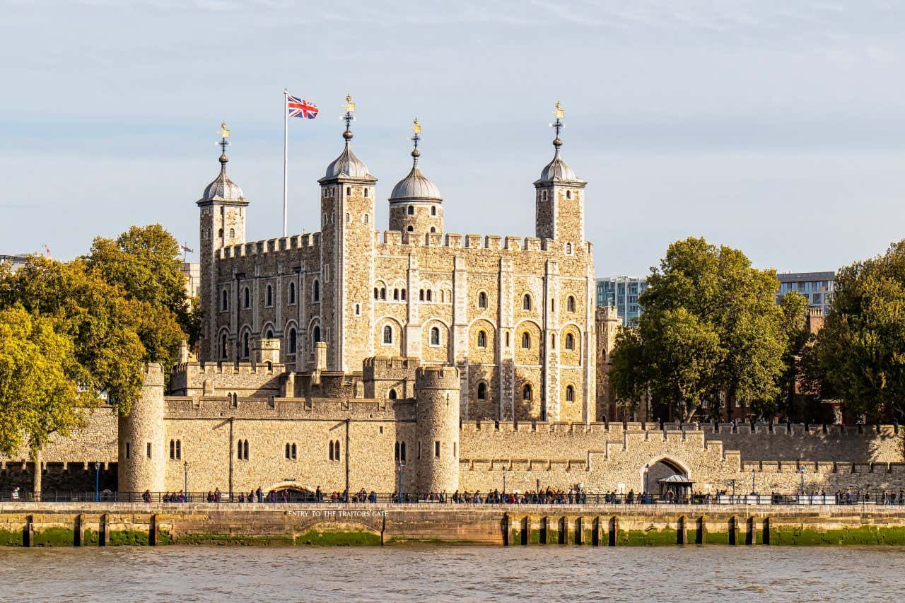 Panorâmica da Torre de Londres com muitos turistas do lado de fora e uma bandeira do Reino Unido no topo