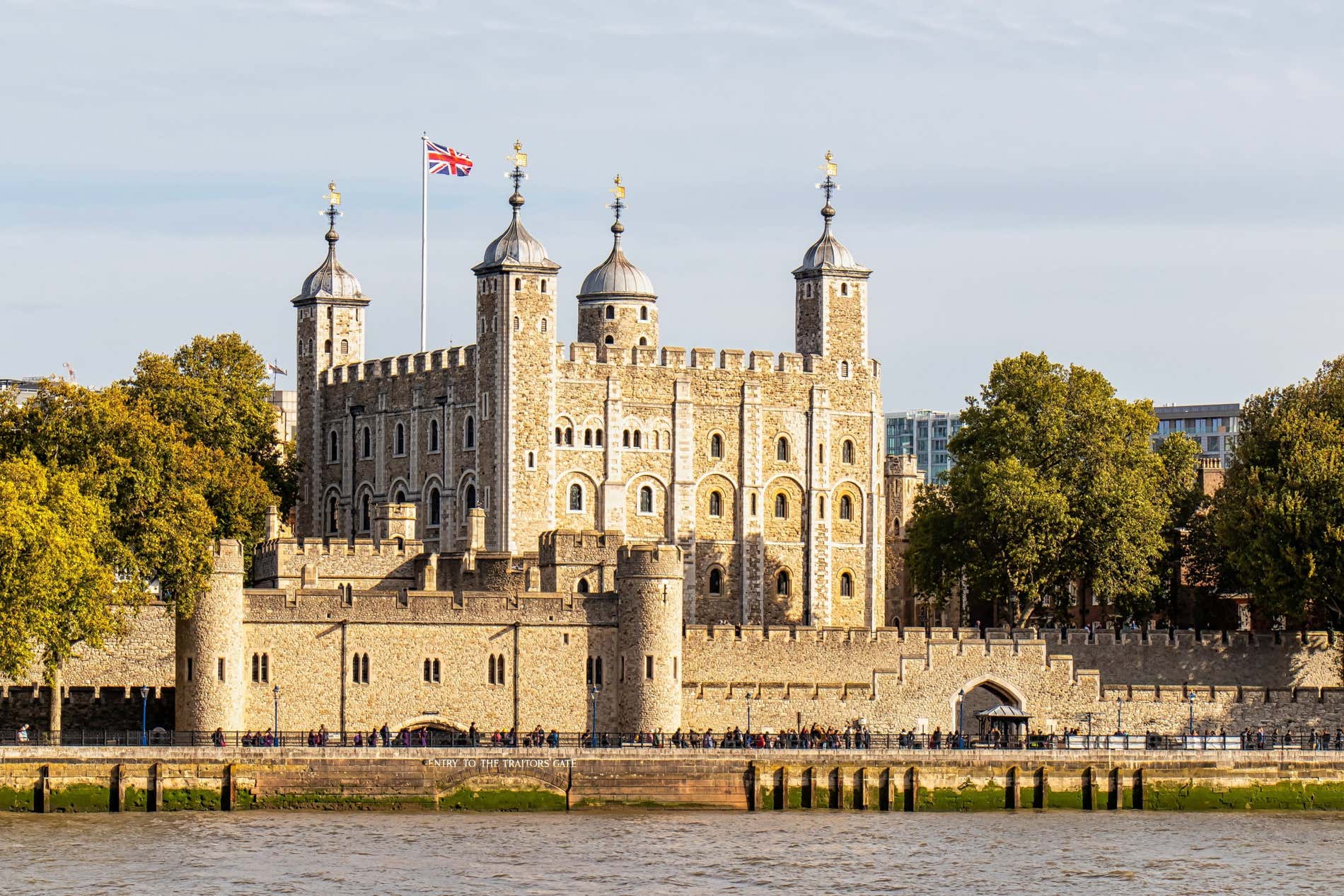 Vista panoramica della Torre di Londra con molti turisti all'esterno e una bandiera britannica sul tetto