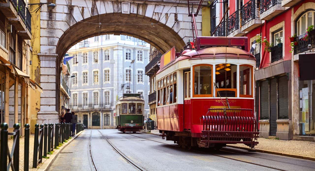 Dois bondes passando por uma rua estreita no centro de Lisboa, uma das capitais europeias para visitar em 2024