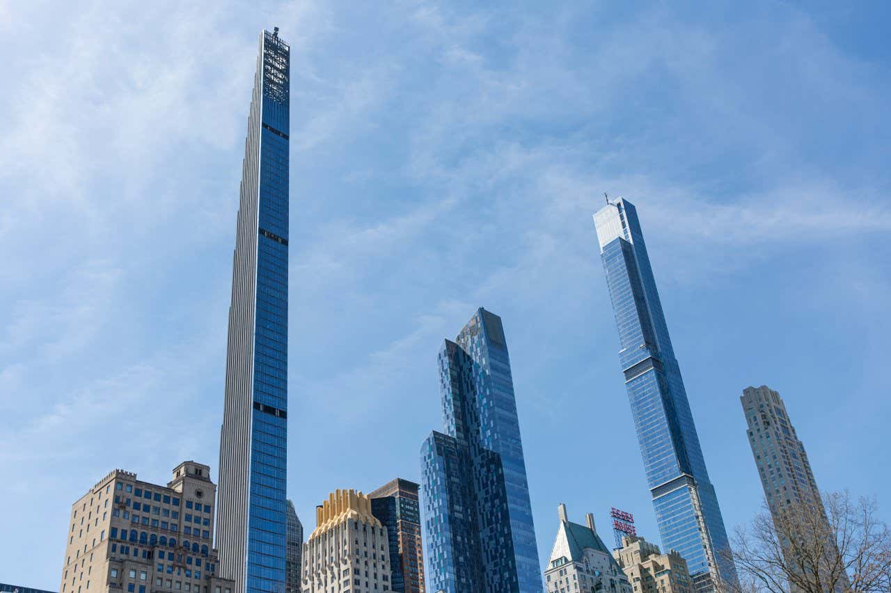 A shot of Steinway Tower and other skyscrapers seen from ground-level, wispy clouds in the sky above