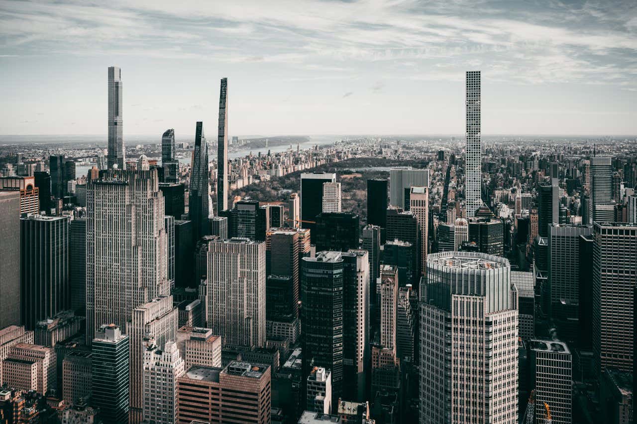 A shot of Central Park Tower and other skyscrapers seen from ground-level, wispy clouds in the sky above