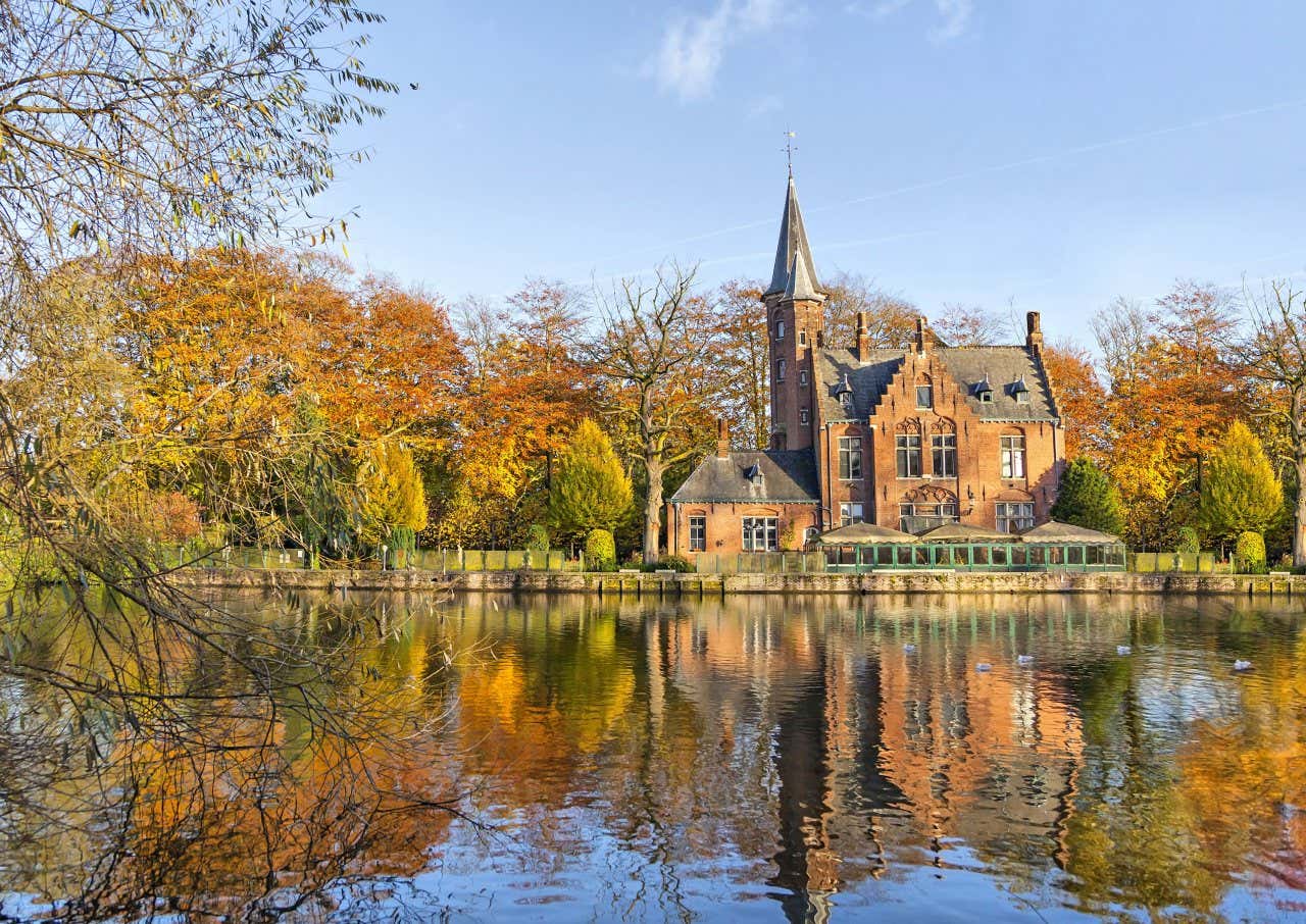 Un lac entouré de végétation automnale et une maison de style flamand
