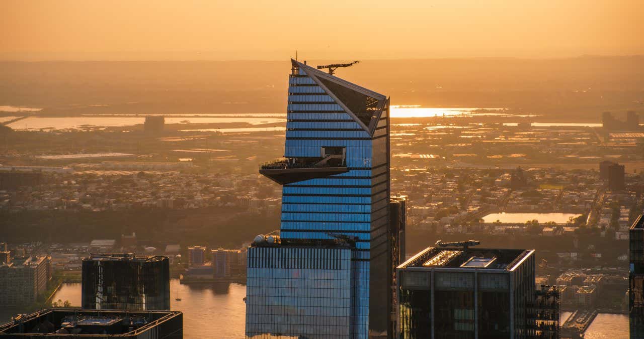 Skyscraper 30 Hudson Yards with a helicopter flying around it in the evening