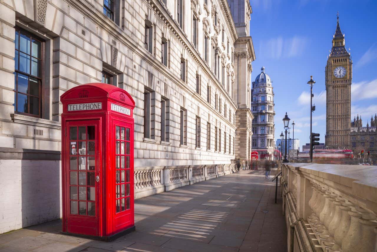 A red telephone box on the corner of a central London street with Big Ben in the background.