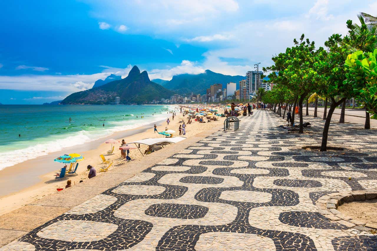 A view of Rio de Janeiro's seafront, with some sunbathers and the iconic mountains in the background.