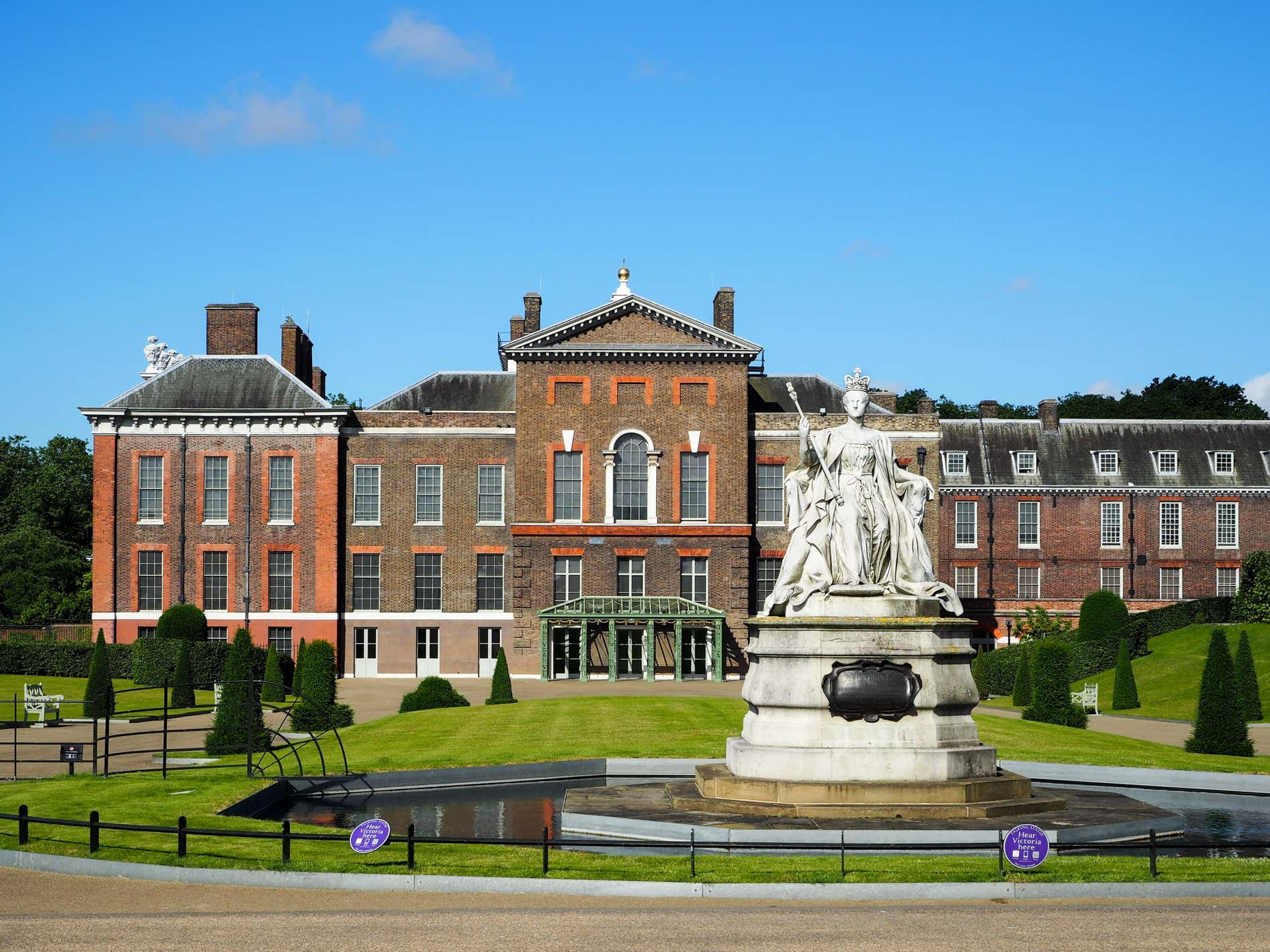 Facciata del Palazzo di Kensington con davanti la statua della Regina Vittoria al centro di un laghetto