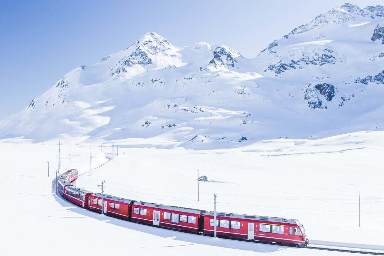 The red Jungfrau Railway in a pristine snow-covered landscape, with the mountains in the background