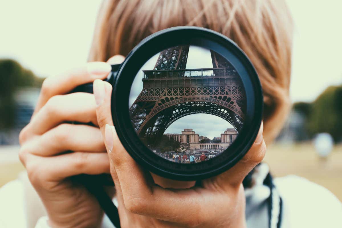 Detail of a professional camera lens reflecting the Eiffel Tower