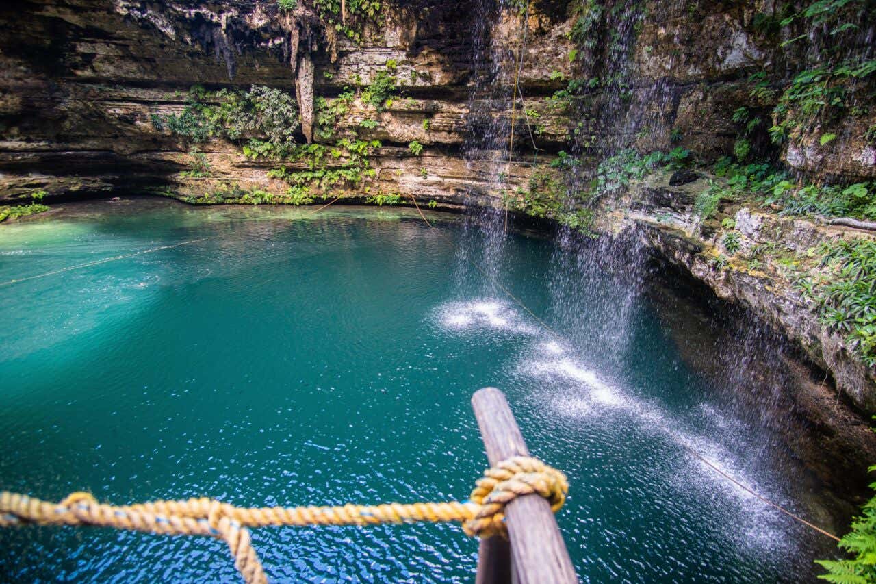Lago azul rodeado por paredes de pedra e vegetação