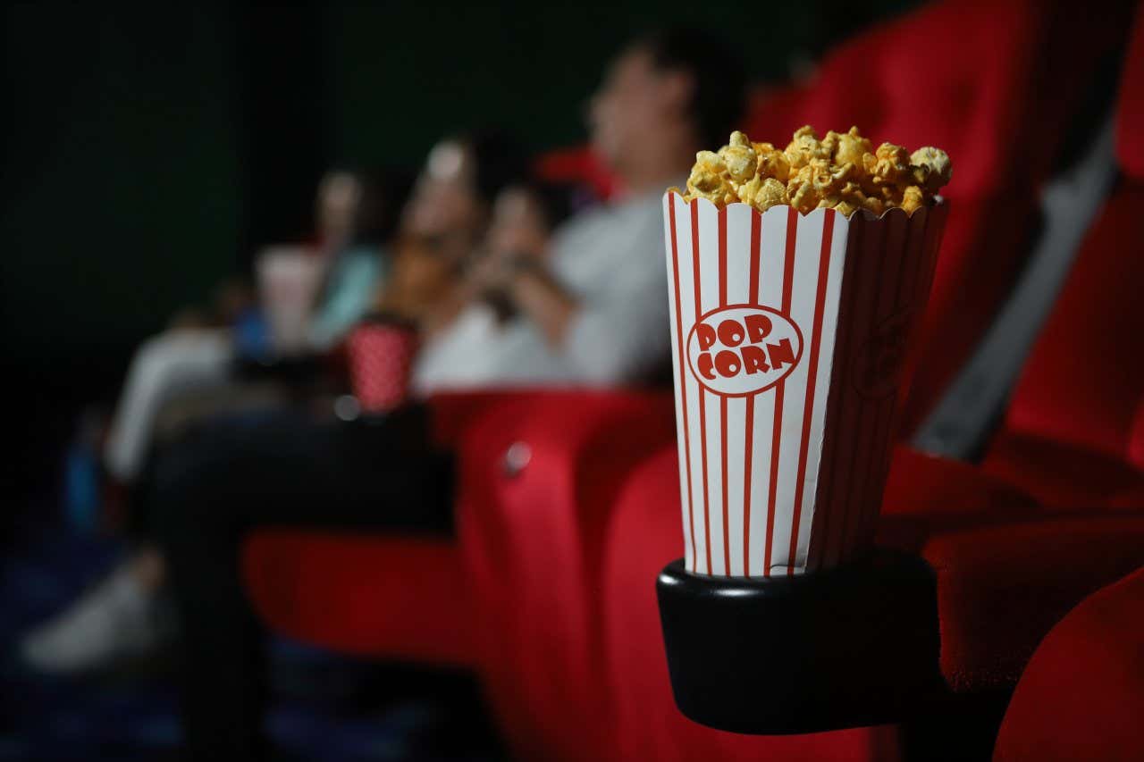 A box filled with popcorn in a cinema with a blurry background.