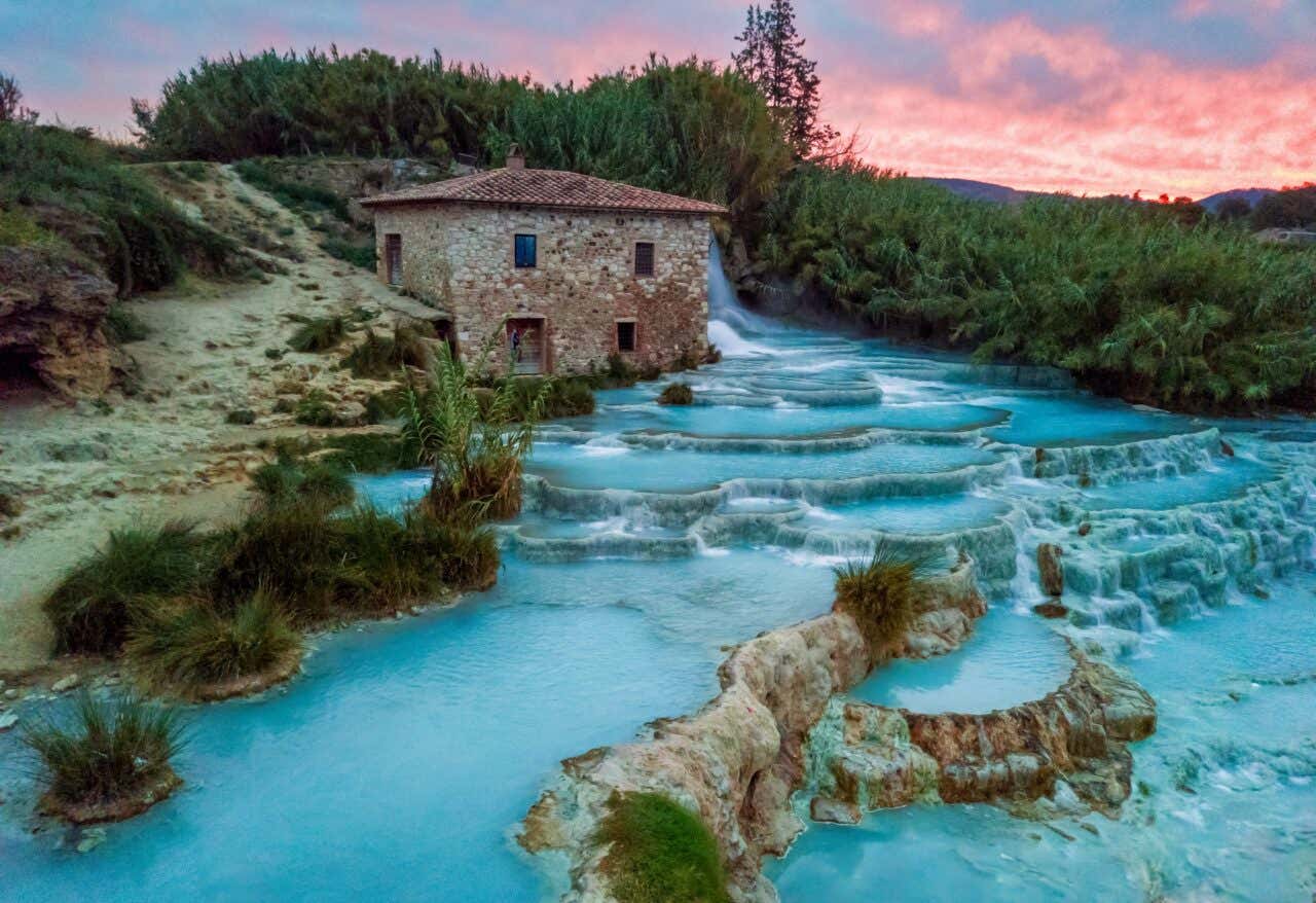Les thermes de Saturnia avec une eau bleu ciel et un ciel rose