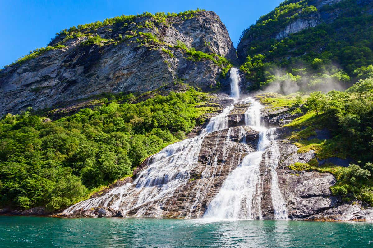 Une cascade jaillissant d'une montagne à la végétation verdoyante dans un fjord