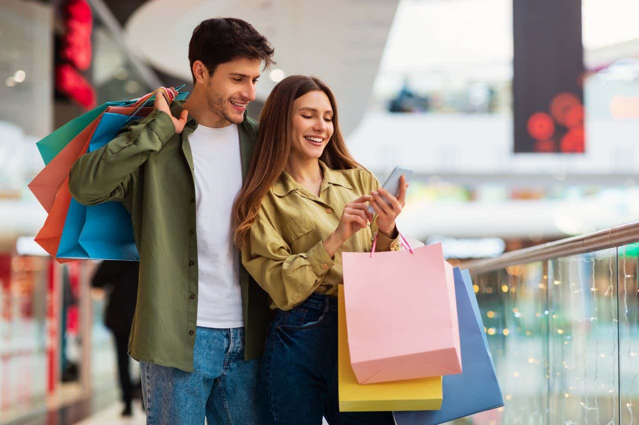 Una mujer y un hombre con muchas bolsas de compras en un centro comercial