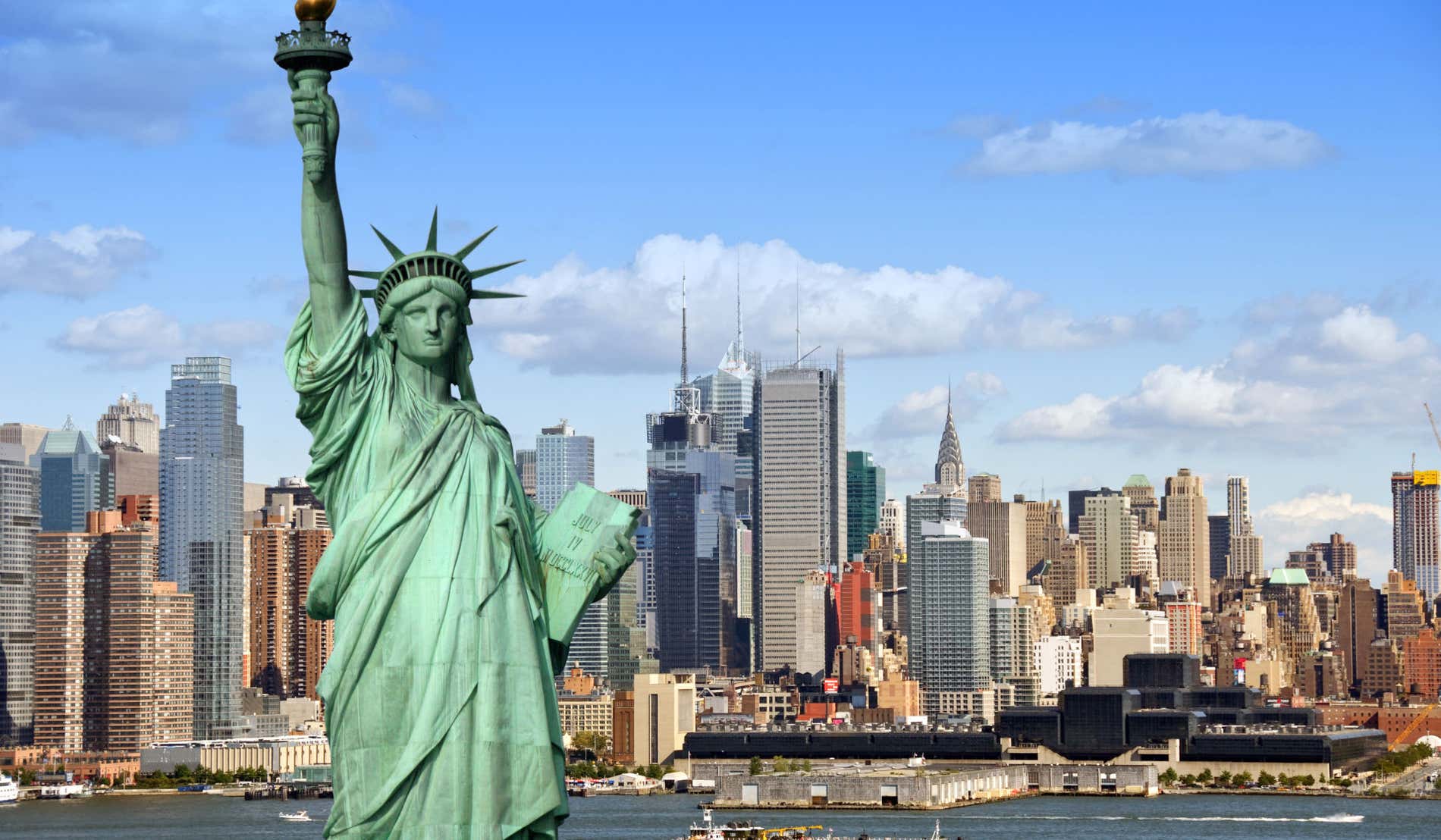 Estatua de la Libertad frente al skyline de los rascacielos de Nueva York en un día con pocas nubes