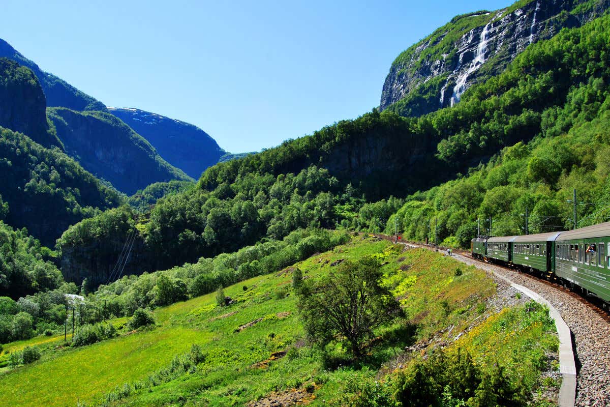 Un train aux fenêtres panoramiques circulant entre de hautes montagnes à la végétation luxuriante