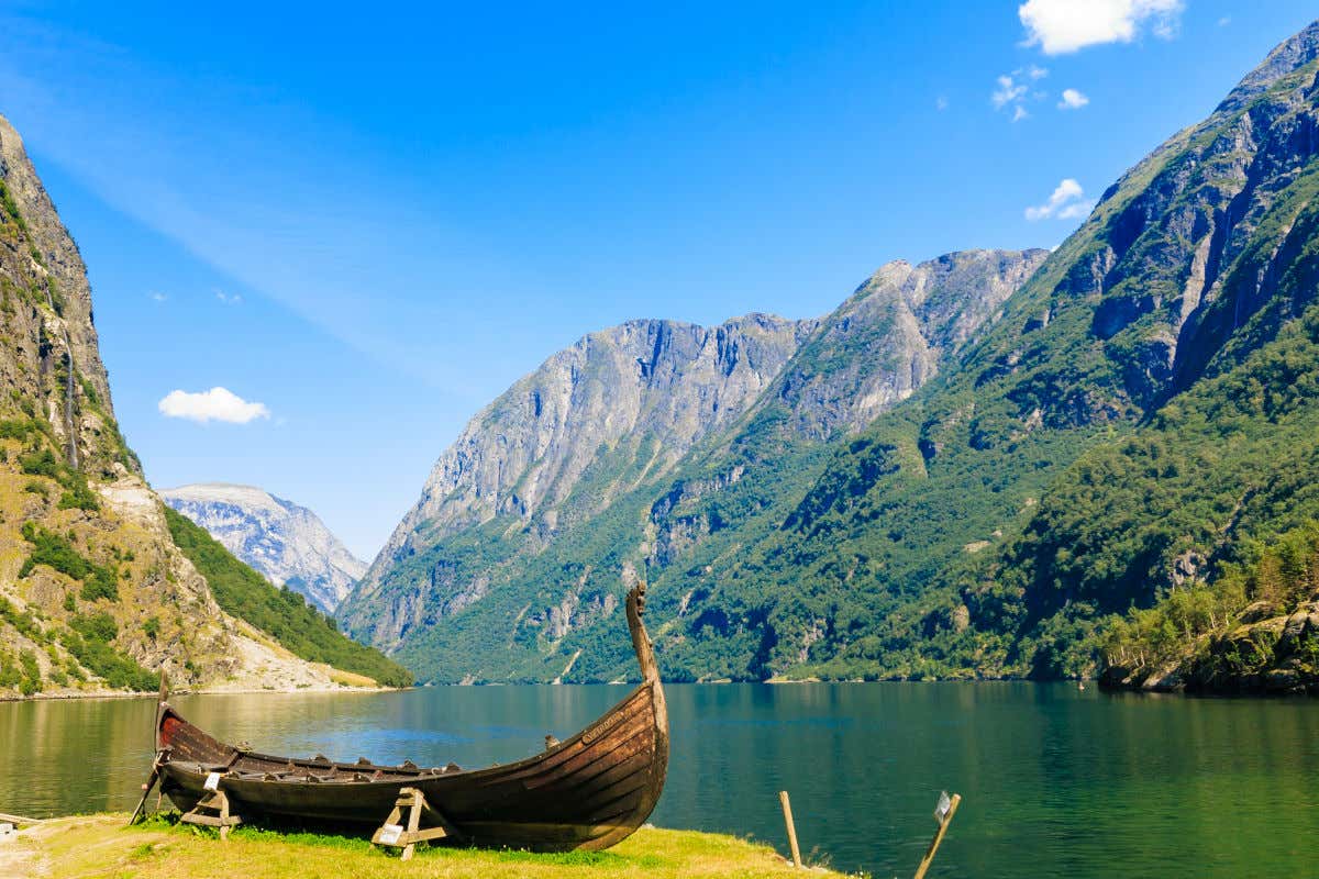 Un bateau viking sur les rives d'un fjord aux eaux émeraude et aux hautes montagnes à la végétation verdoyante