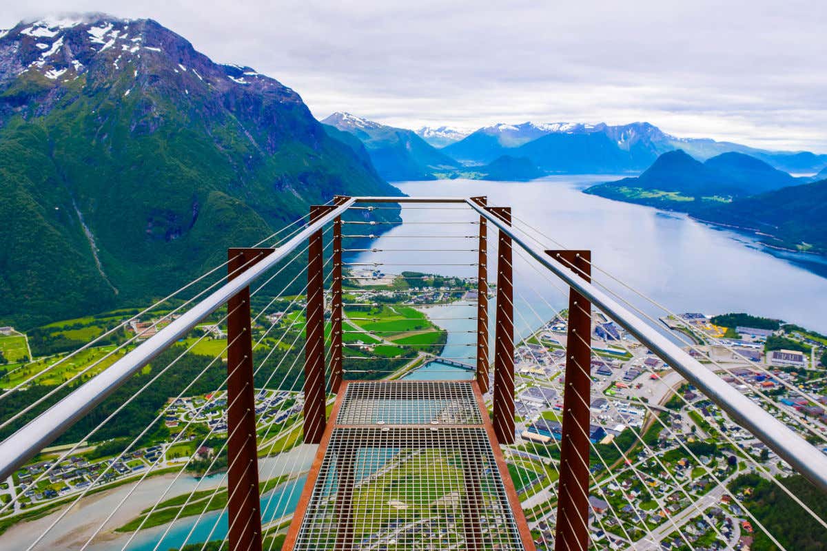 Passerelle suspendue servant de point de vue sur le Romsdalsfjord et plusieurs maisons et montagnes