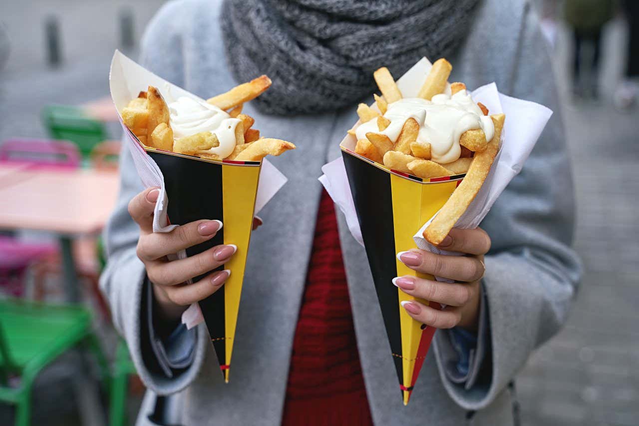 Plano medio de una mujer sujetando dos vasos de cartón de patatas fritas en un día de invierno