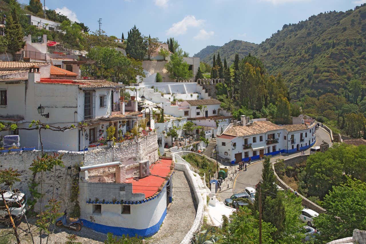 Panoramica del Sacromonte di Granada con case bianche arroccate su una collina e le montagne di fronte
