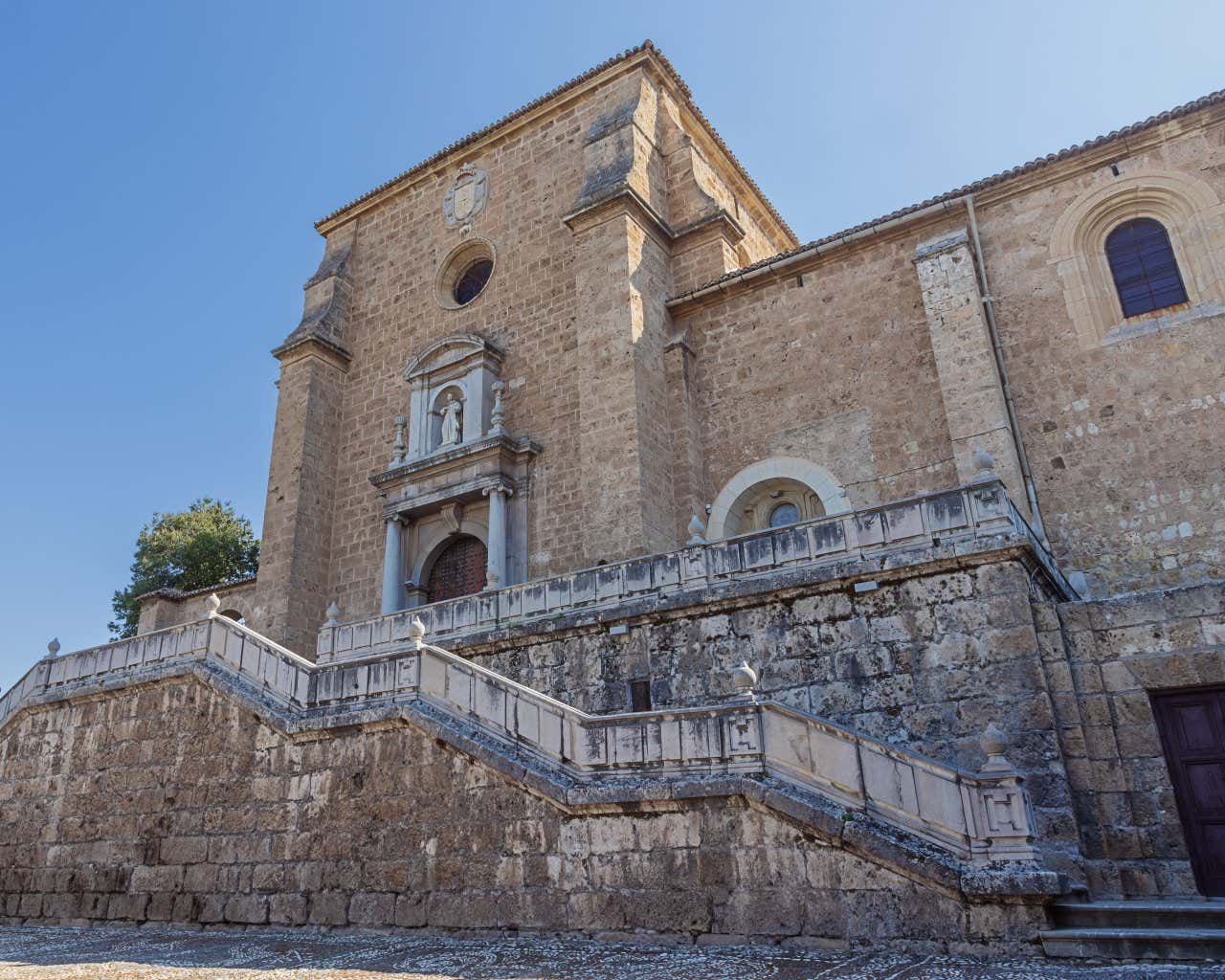 L'ingresso del Monastero della Cartuja a Granada, sollevato da terra e raggiungibile mediante alcune rampe di scale con un cielo azzurro sullo sfondo