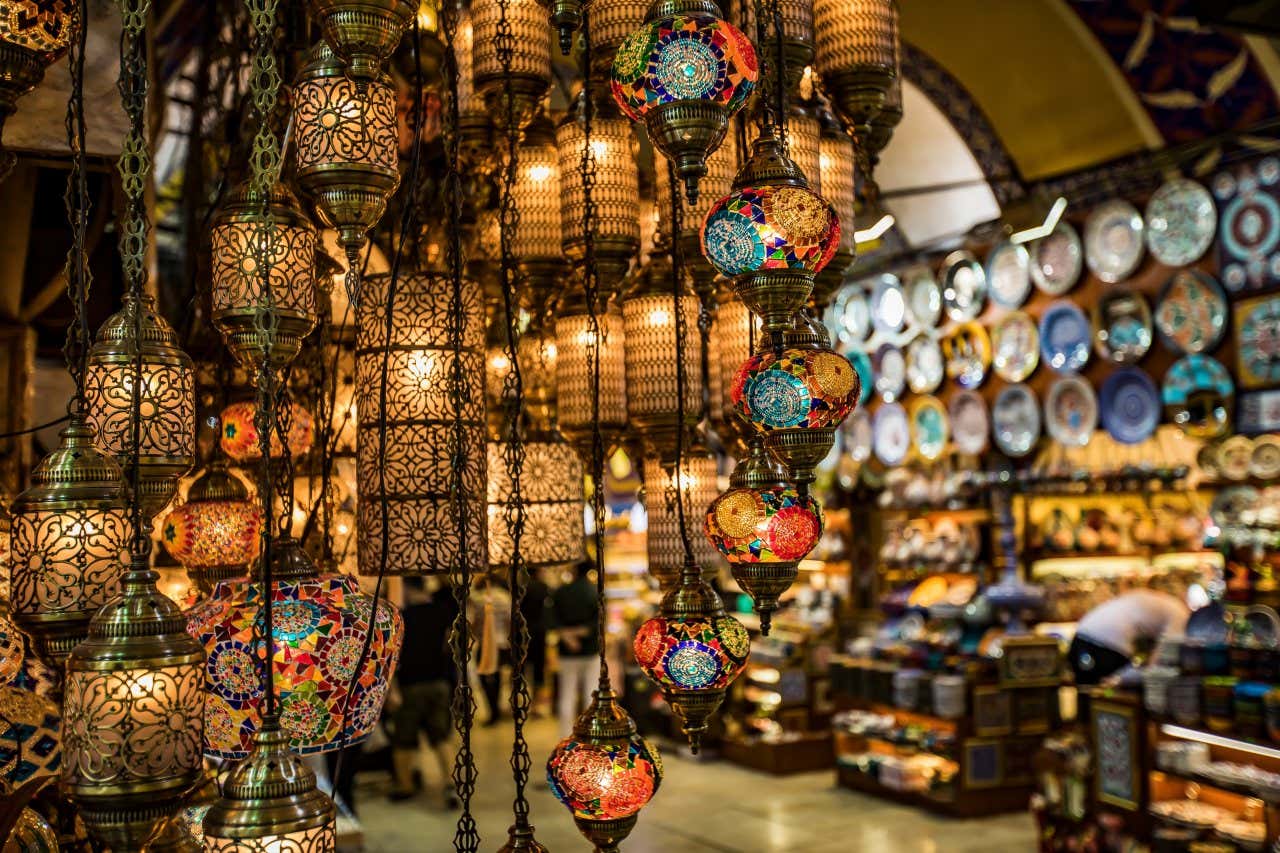 A close-up of lamps in the Grand Bazaar in Istanbul, with a merchant in the background.