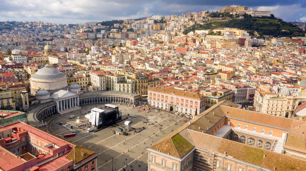 Vista aérea del centro histórico de Nápoles con el barrio Vomero al fondo y unas nubes grisáceas