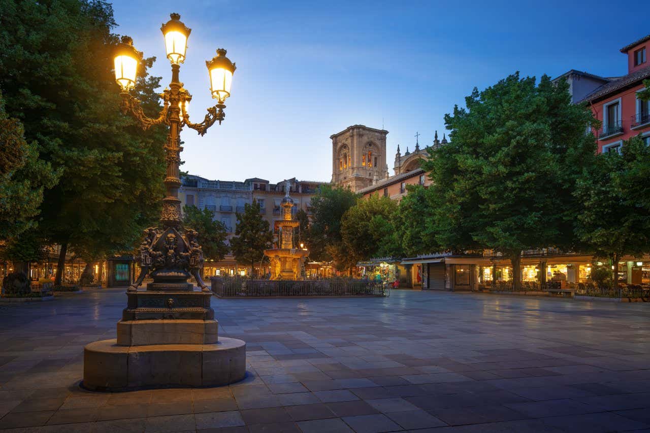 Uno scatto di Plaza de Bib-Rambla di notte, con un lampione illuminato in primo piano e una fontana sullo sfondo