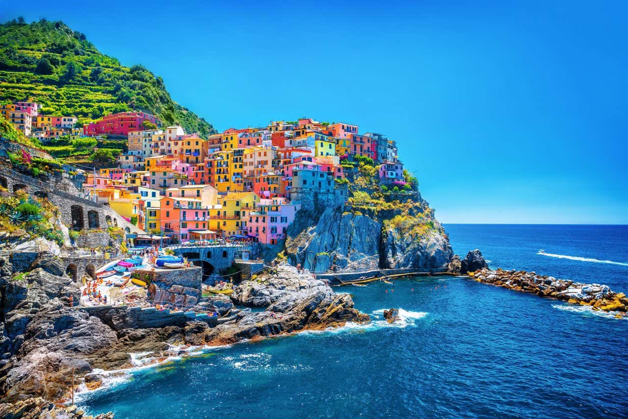 Mar Mediterrâneo banhando um povoado encravado nas rochas repleto de casas coloridas