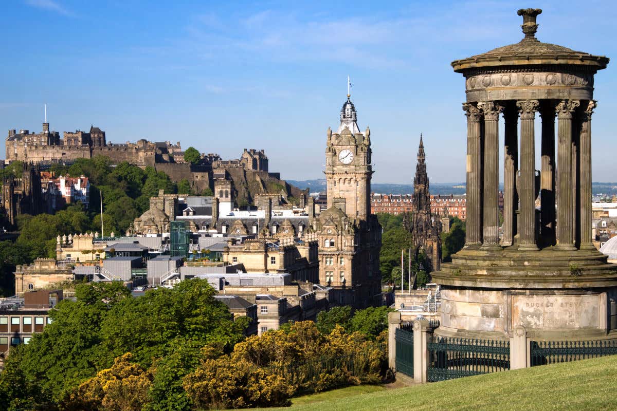Un templete de un parque de Edimburgo desde el que se puede ver el castillo de la ciudad en una alta colina