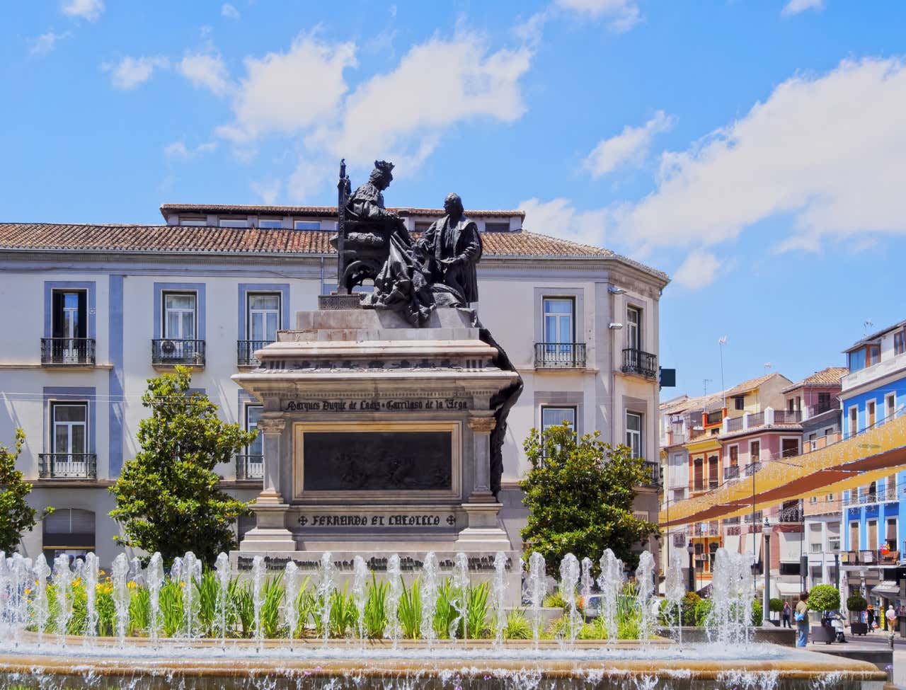 Escultura de Isabel la Católica en una plaza de Granada con el cielo azul de fondo