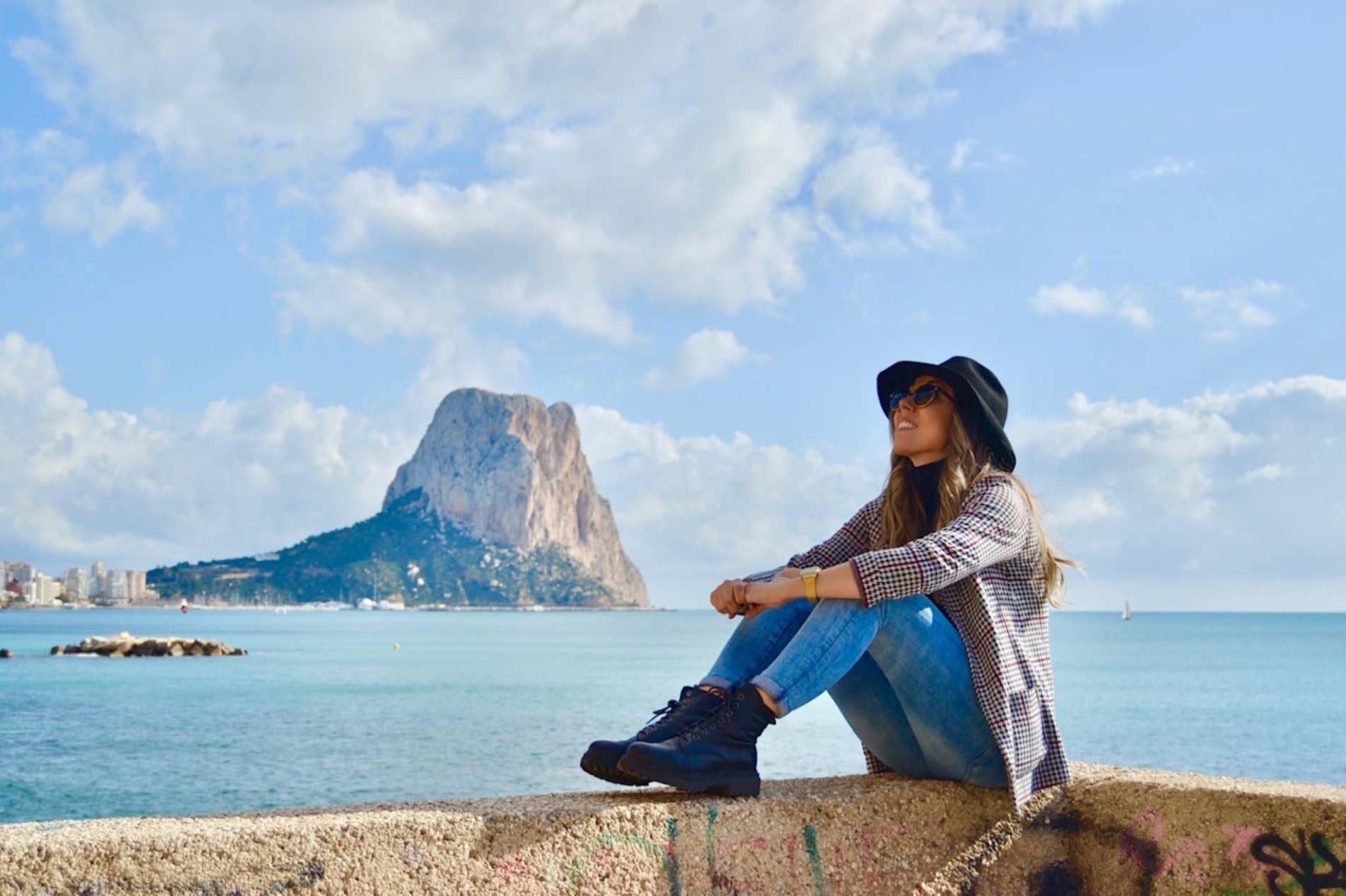 Laura sentada con el mar y una colina de fondo