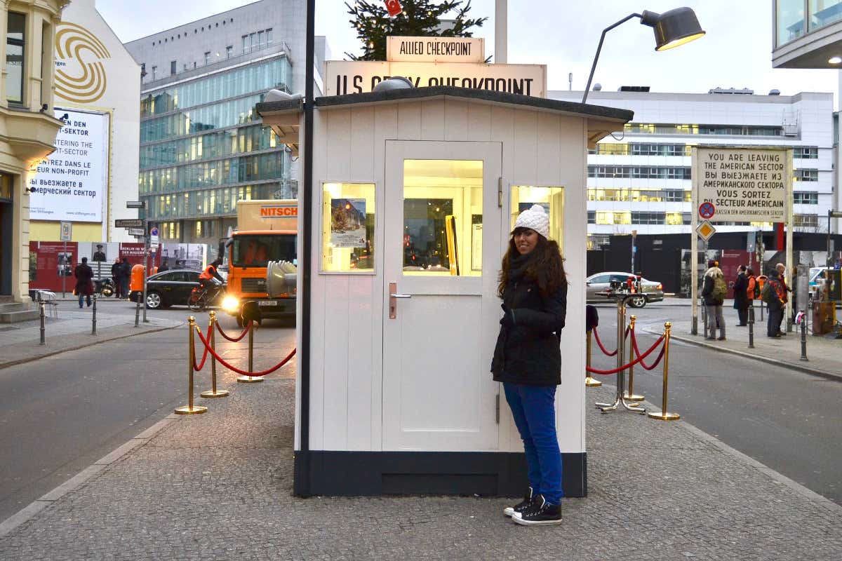 Una chica frente al ckepoint Charlie de Berlín