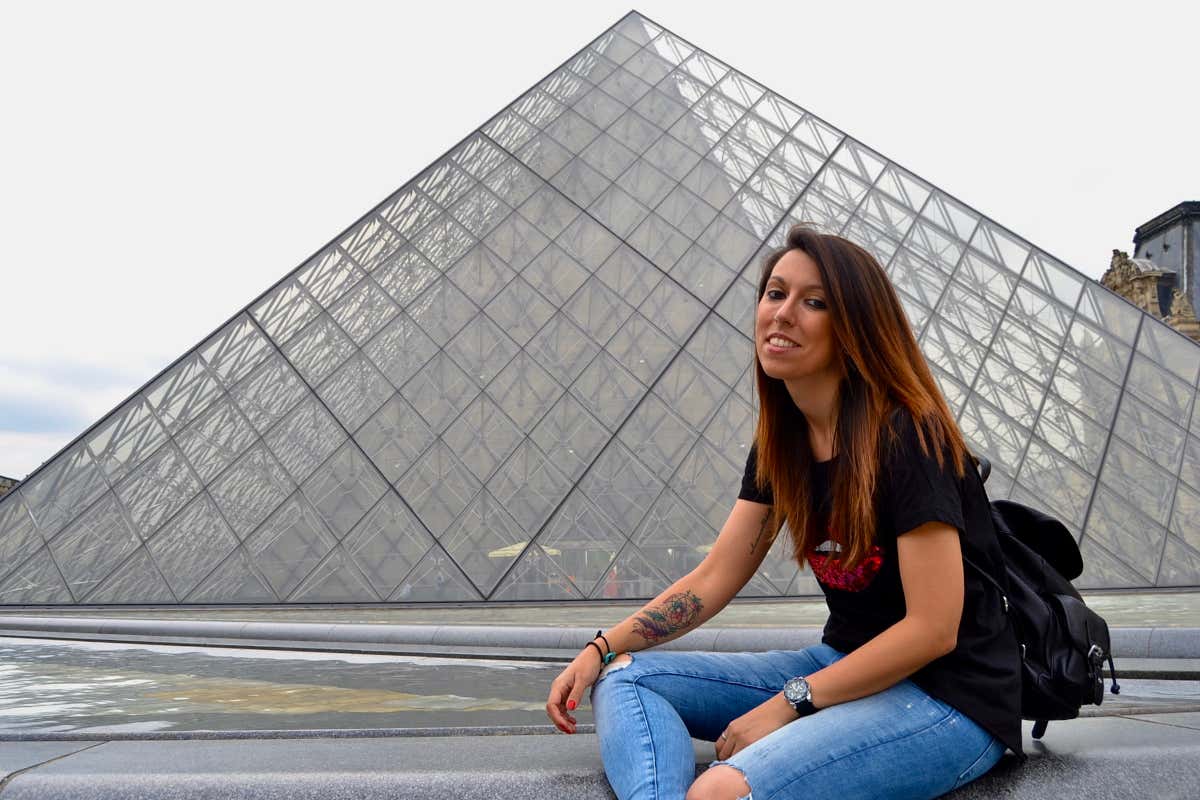 Una chica frente a la pirámide del Museo del Louvre en París