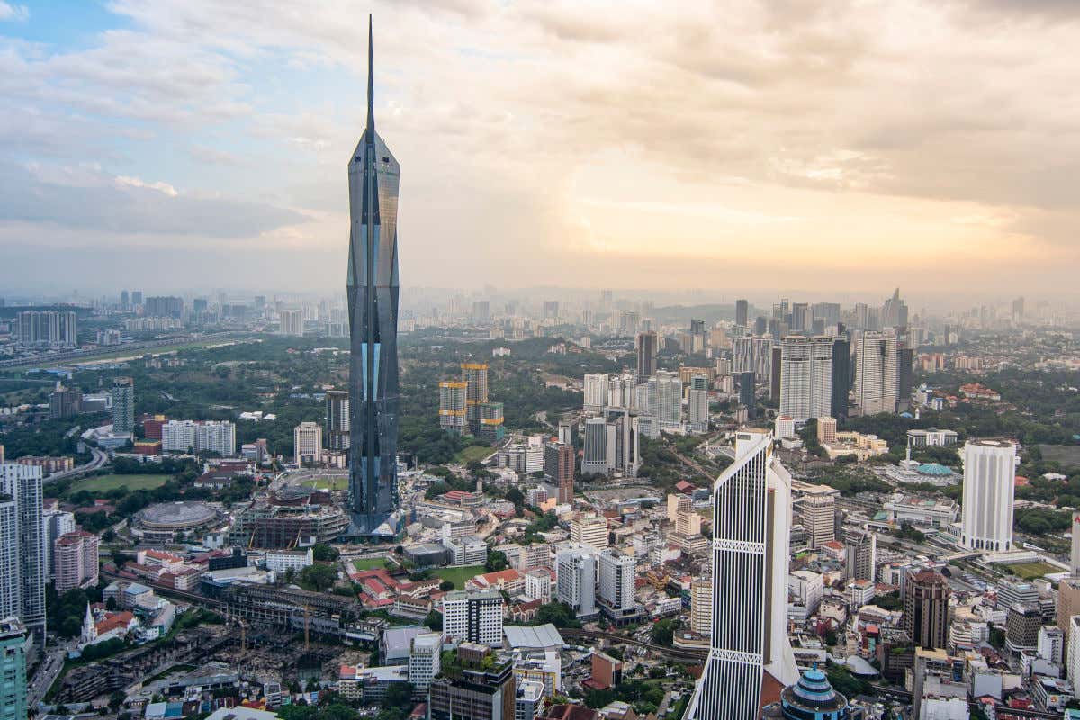 Merdeka 118 uno de los edificios más altos del mundo junto a otros rascacielos y parques urbanos al atardecer