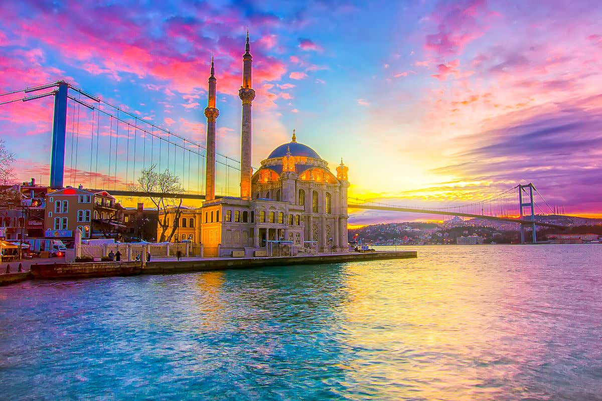 Una mezquita en las orillas del estrecho de Estambul y junto al puente al atardecer