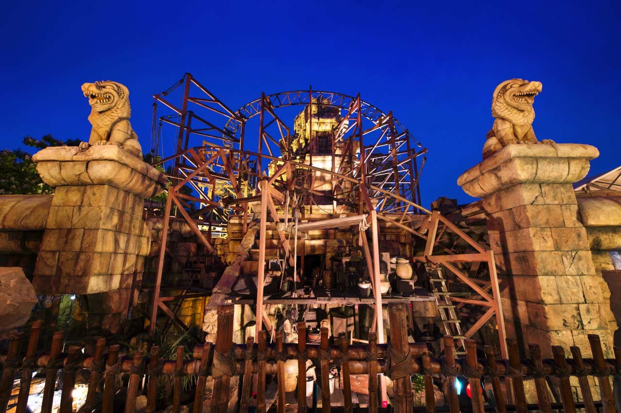 The entrance of Indiana Jones and the Temple of Peril at night, with a midnight blue sky in the background, behind the rollercoaster.