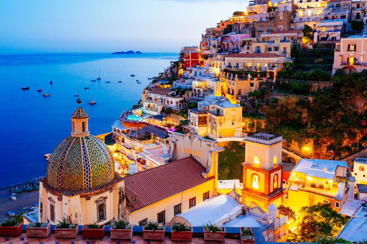 Las casas de Positano se extienden por una colina frente al mar y se iluminan al anochecer