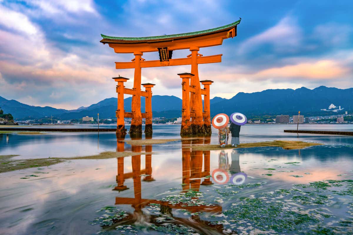 Un torii, una puerta japonesa tradicional, en mitad de un manantial y junto a una pareja de enamorados vestidos con kimonos