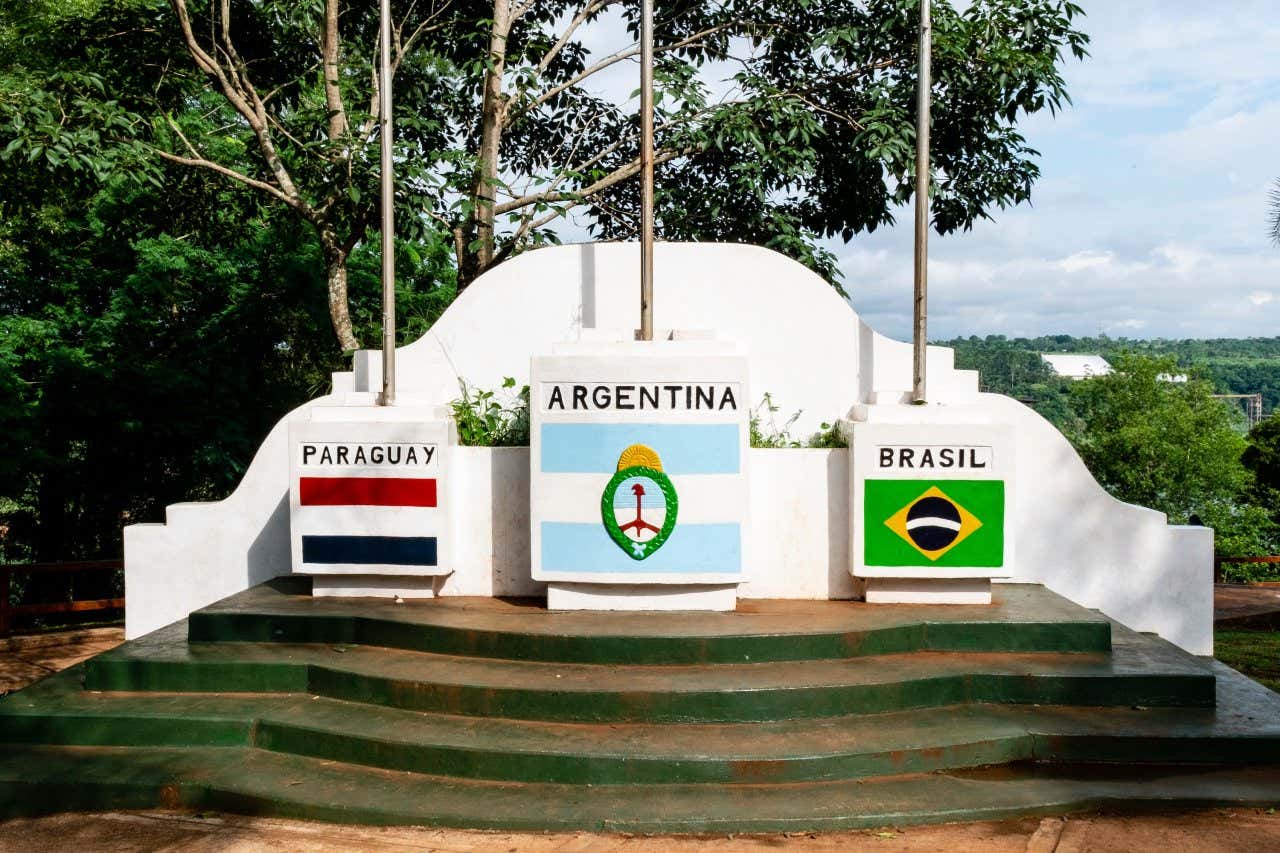 Um monumento com as bandeiras da Argentina ao centro e do Paraguai e do Brasil ao lado