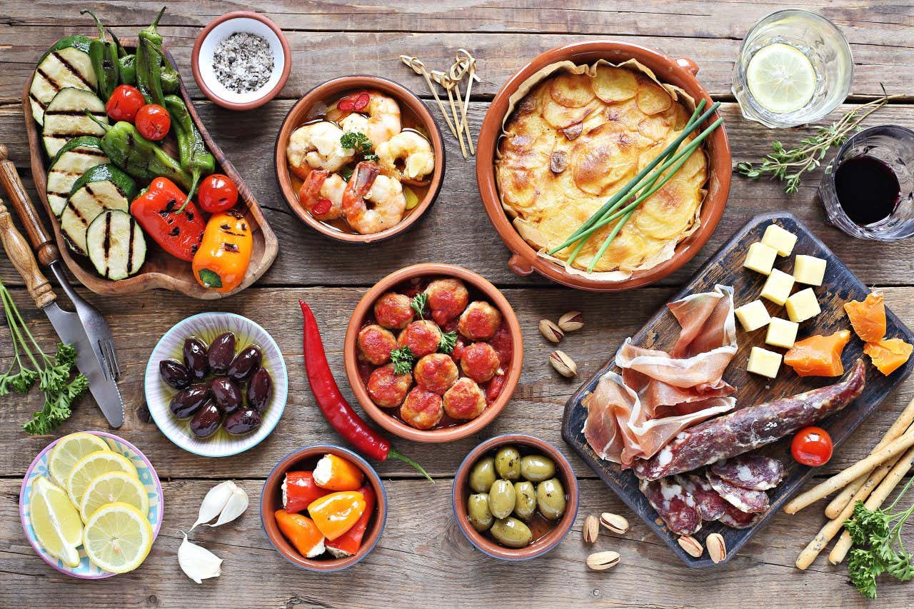 Vue sur une table sur laquelle sont disposés plusieurs petites assiettes, plats, et planches remplis de tapas, à Grenade