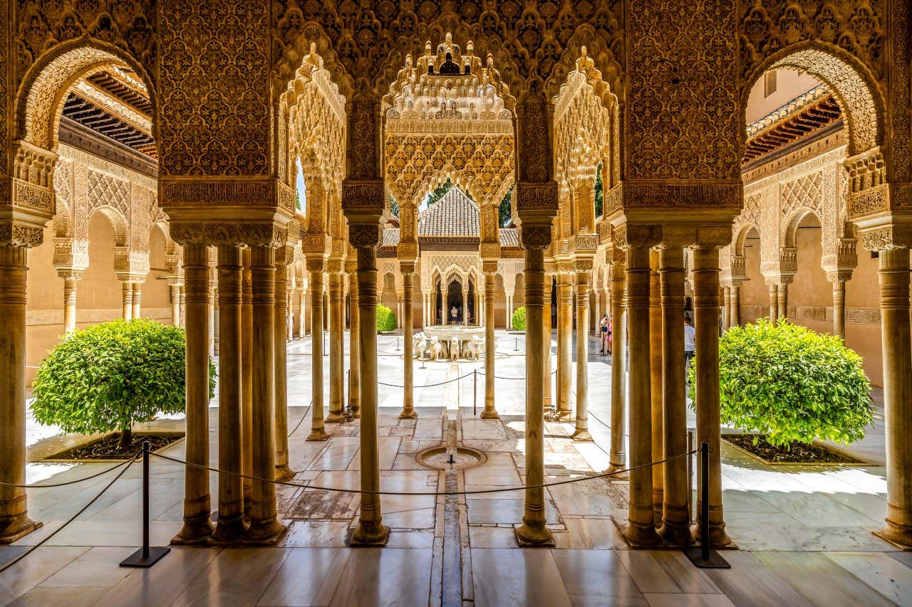 Vue sur les colonnes et leurs détails architecturaux, cour des Lions en arrière-plan, un des lieux les plus connus de l'Alhambra de Grenade