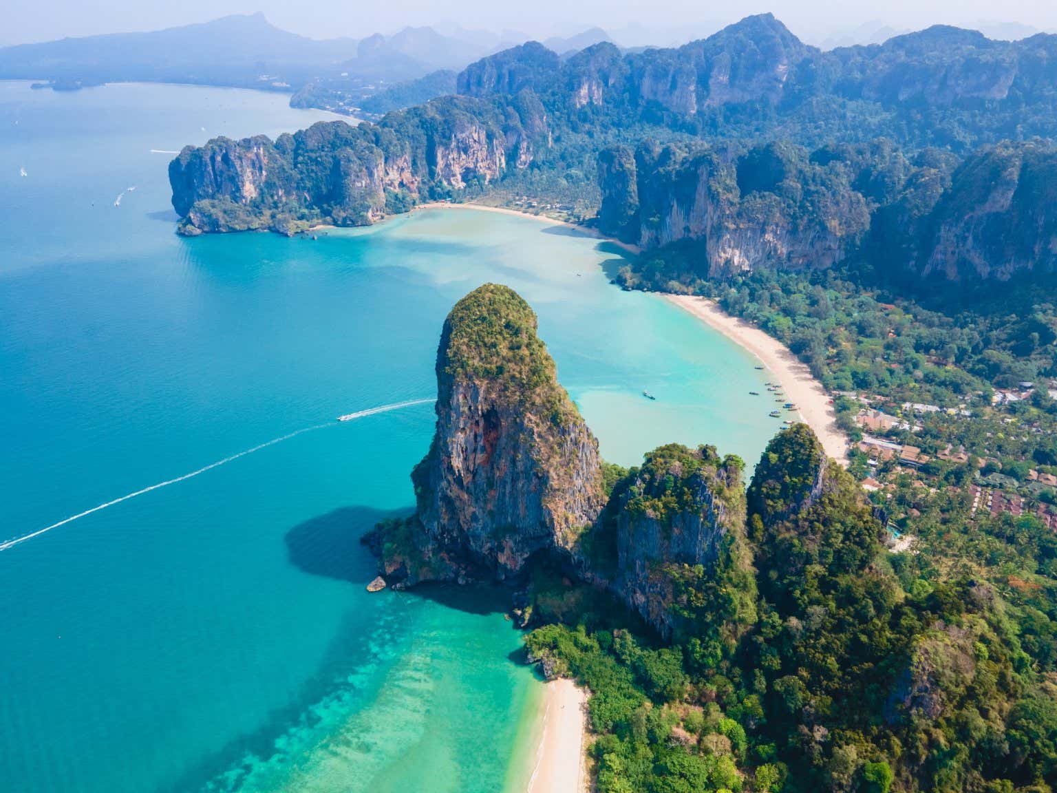 Un paesaggio idilliaco di Phuket, con spiagge bianche, un mare turchese e alcune alte scogliere a picco sull'acqua