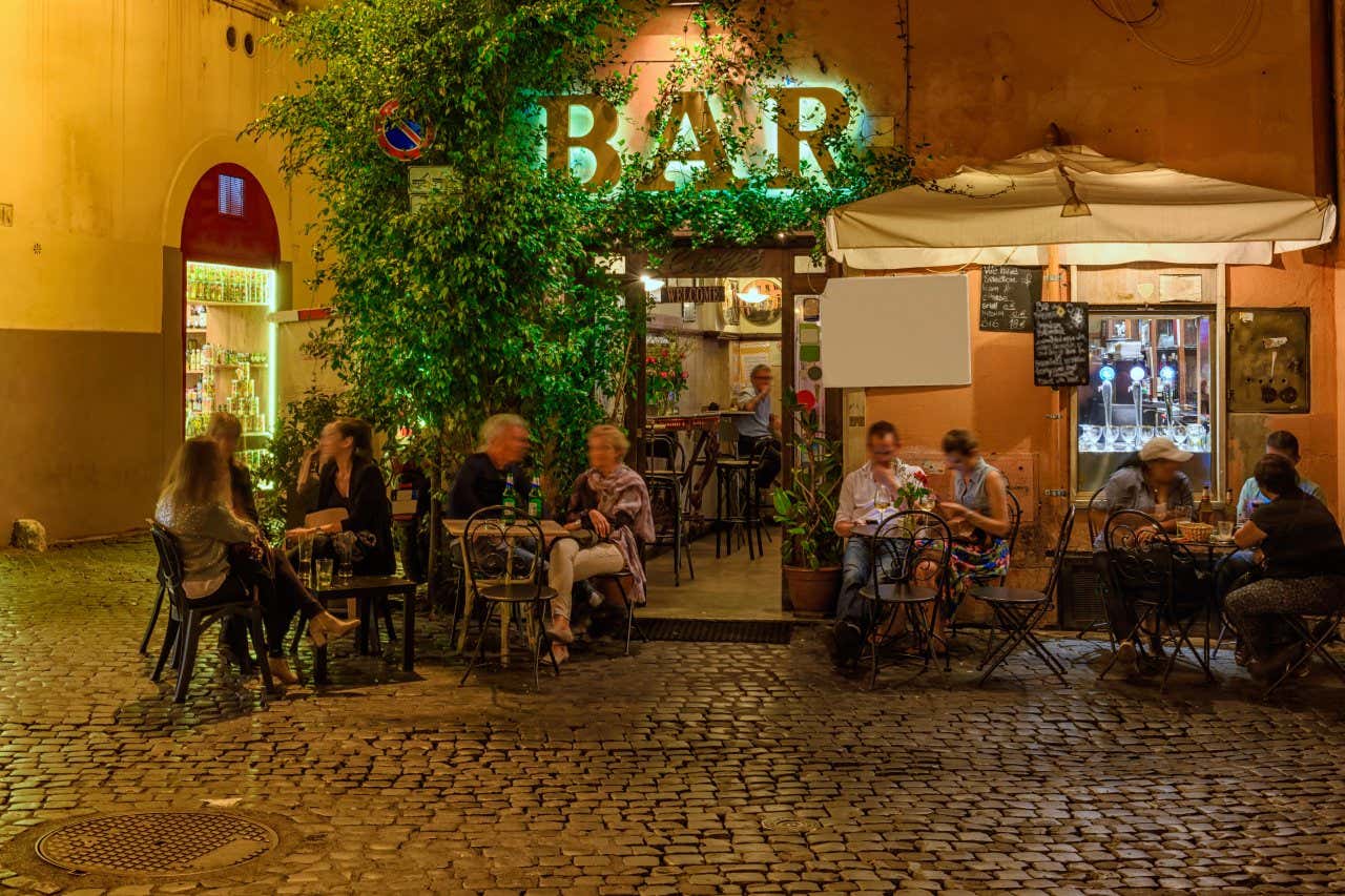 Un bar di Trastevere, a Roma, con alcune persone sedute all'esterno