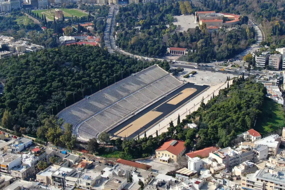 Vista aérea do estádio Panatenaico de Atenas rodeado de árvores e pela cidade
