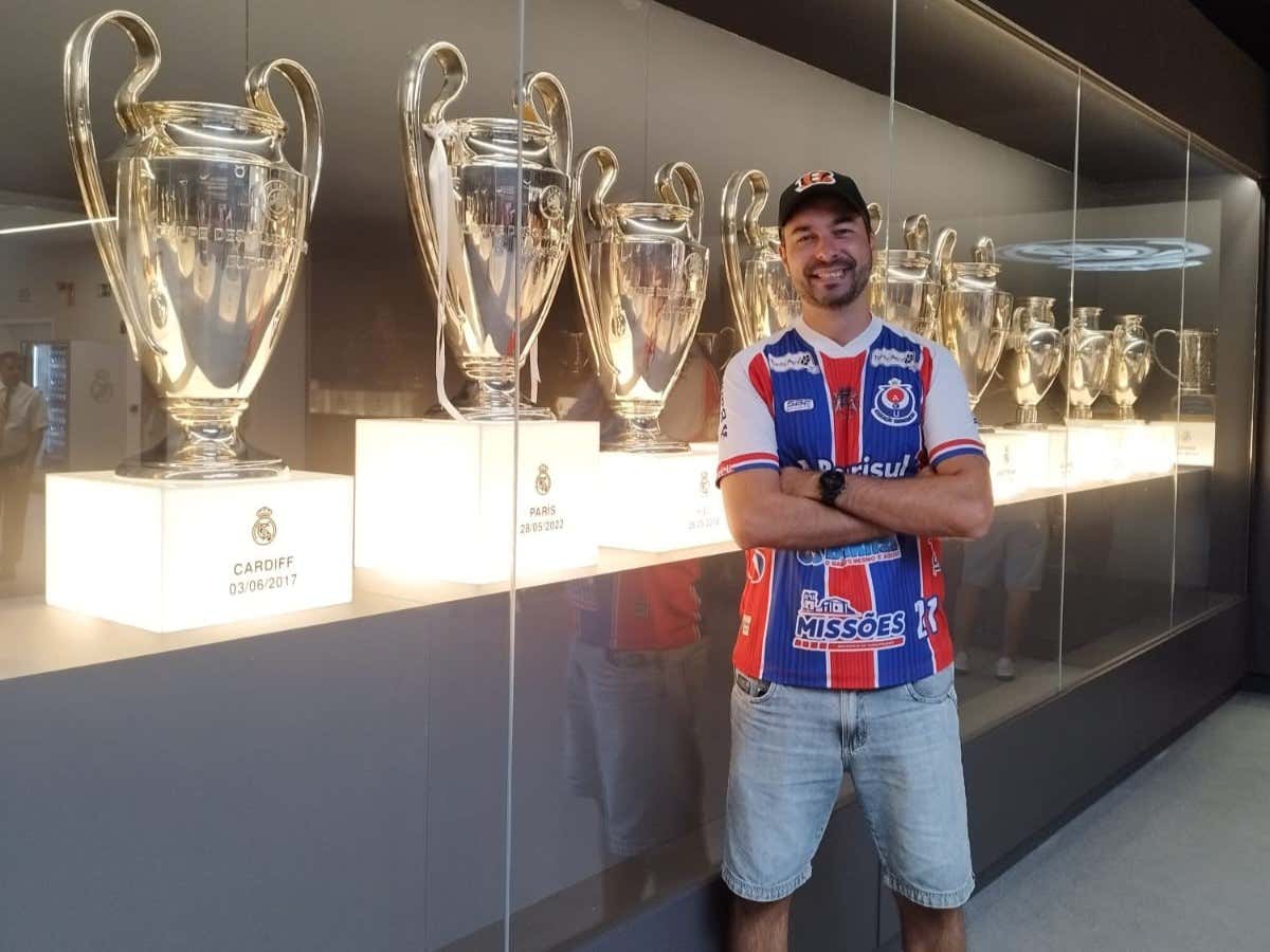Un joven sonriendo para una foto frente a unos trofeos en un museo