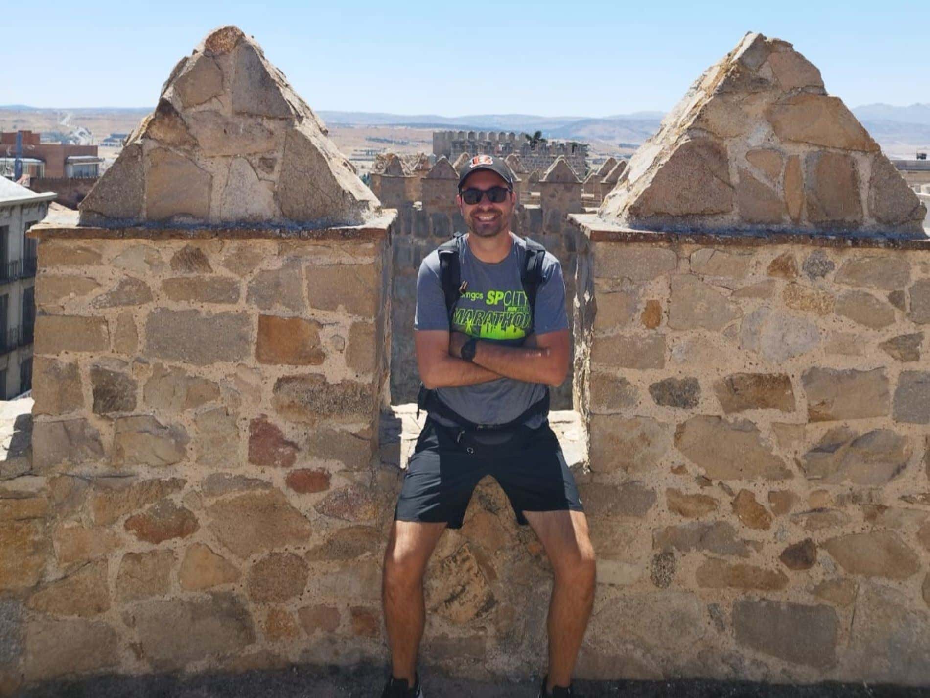 Un hombre sonriendo en lo alto de un edificio histórico de piedra