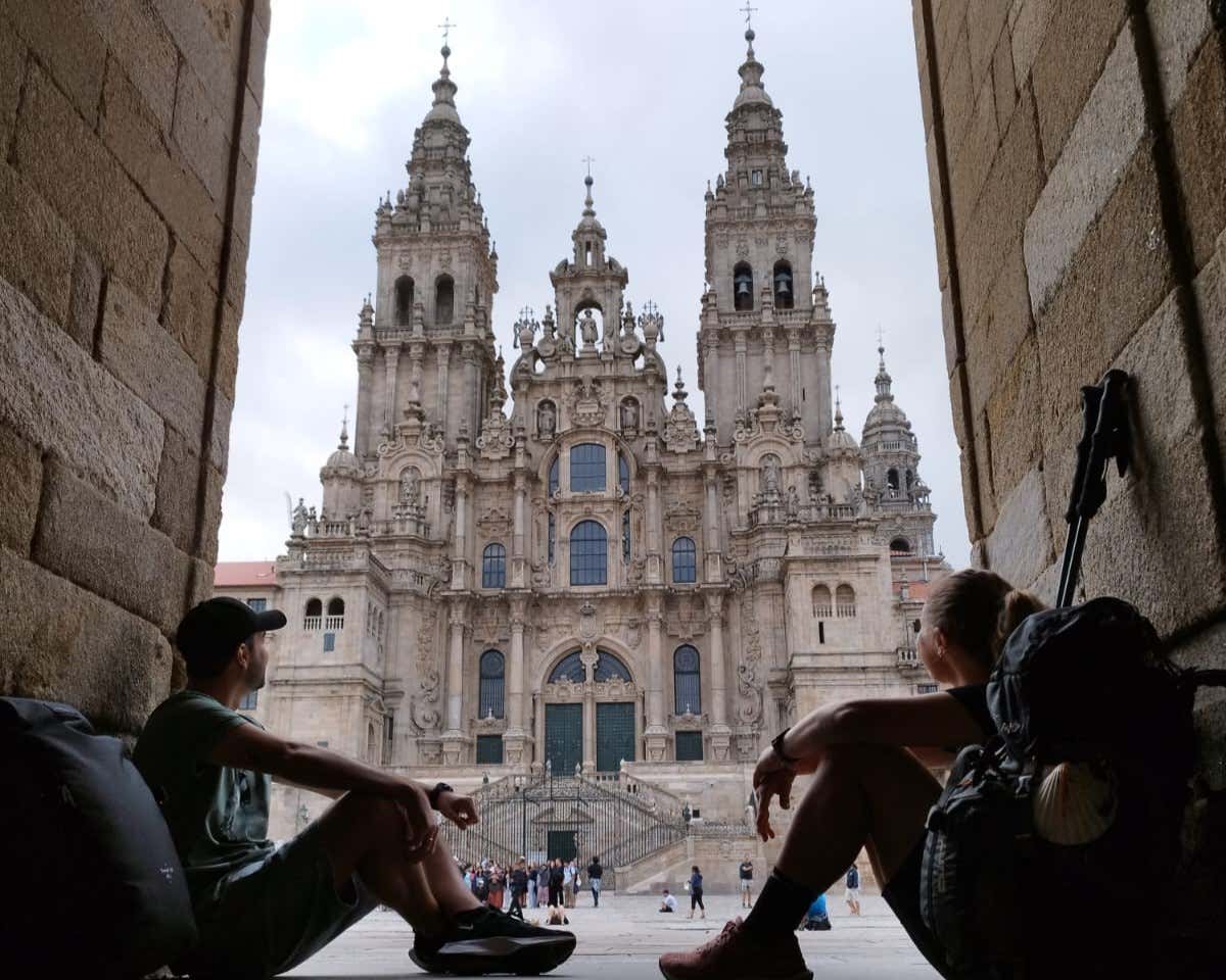 Una pareja sentados contemplando una catedral en Santiago de Compostela