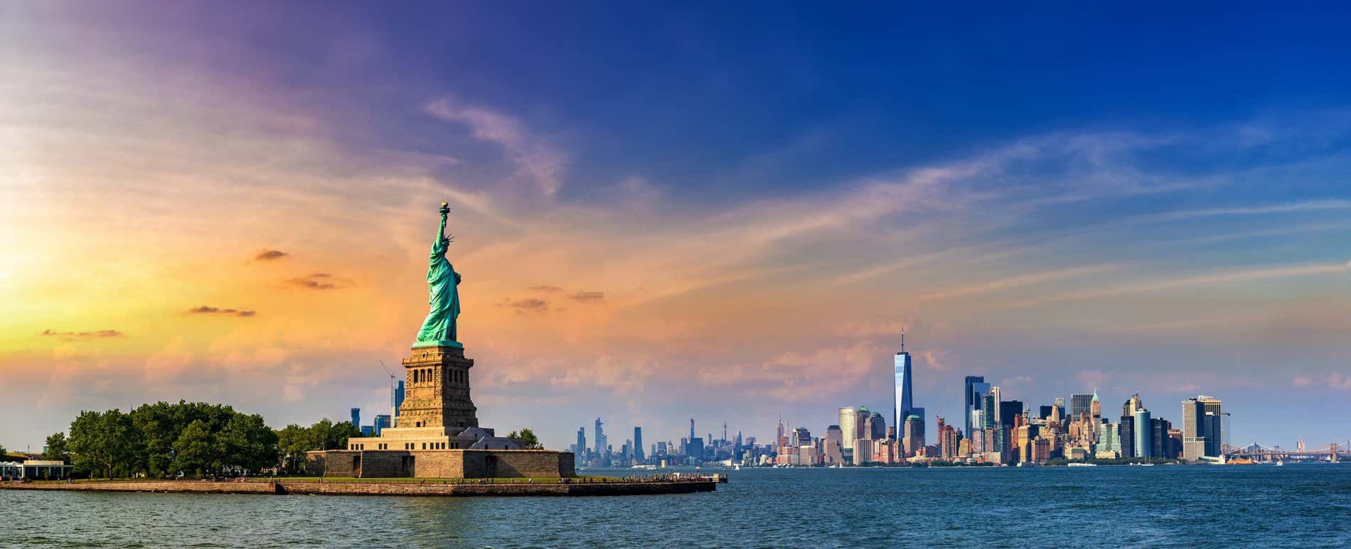 The Statue of Liberty and skyscrapers of New York at sunset.