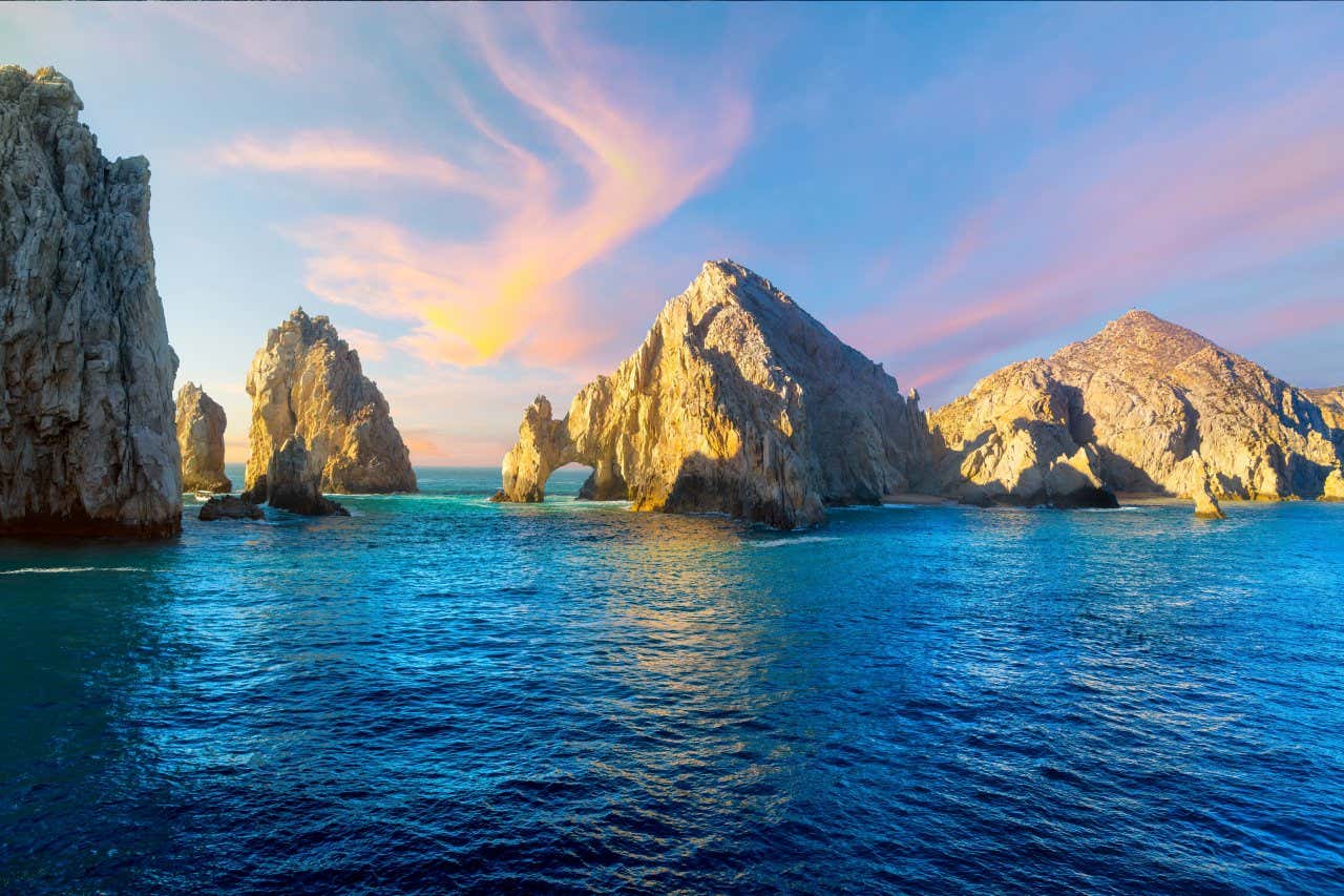 Grey rock formations and arches in the sea under a light purple and blue sky: the perfect family vacation spot