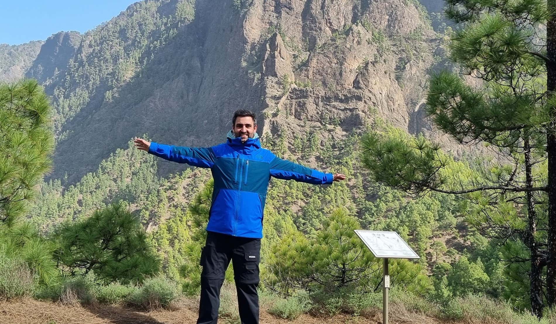 Un hombre con los brazos extendidos frente a una montaña